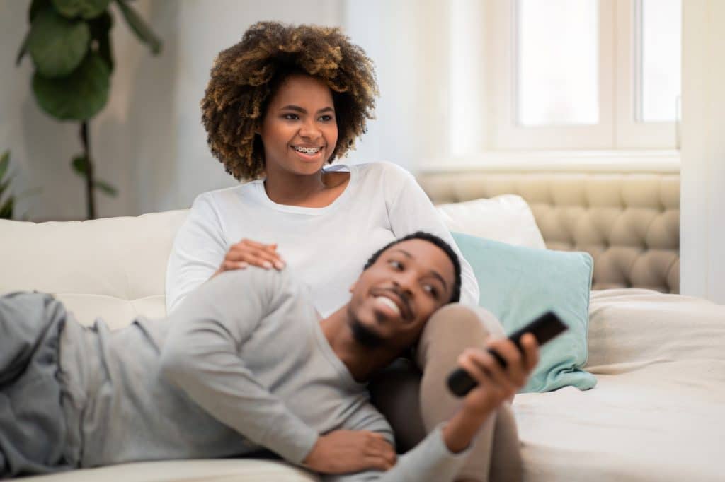 African american lovers watching TV show, home interior
