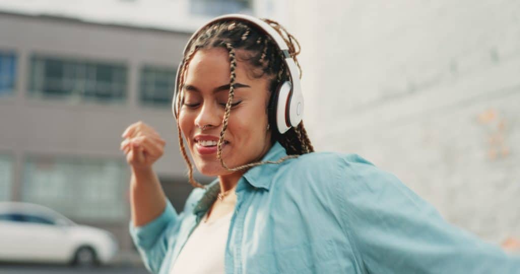 Woman, dancing and listening to music in the city with headphones for audio streaming in the outdoo