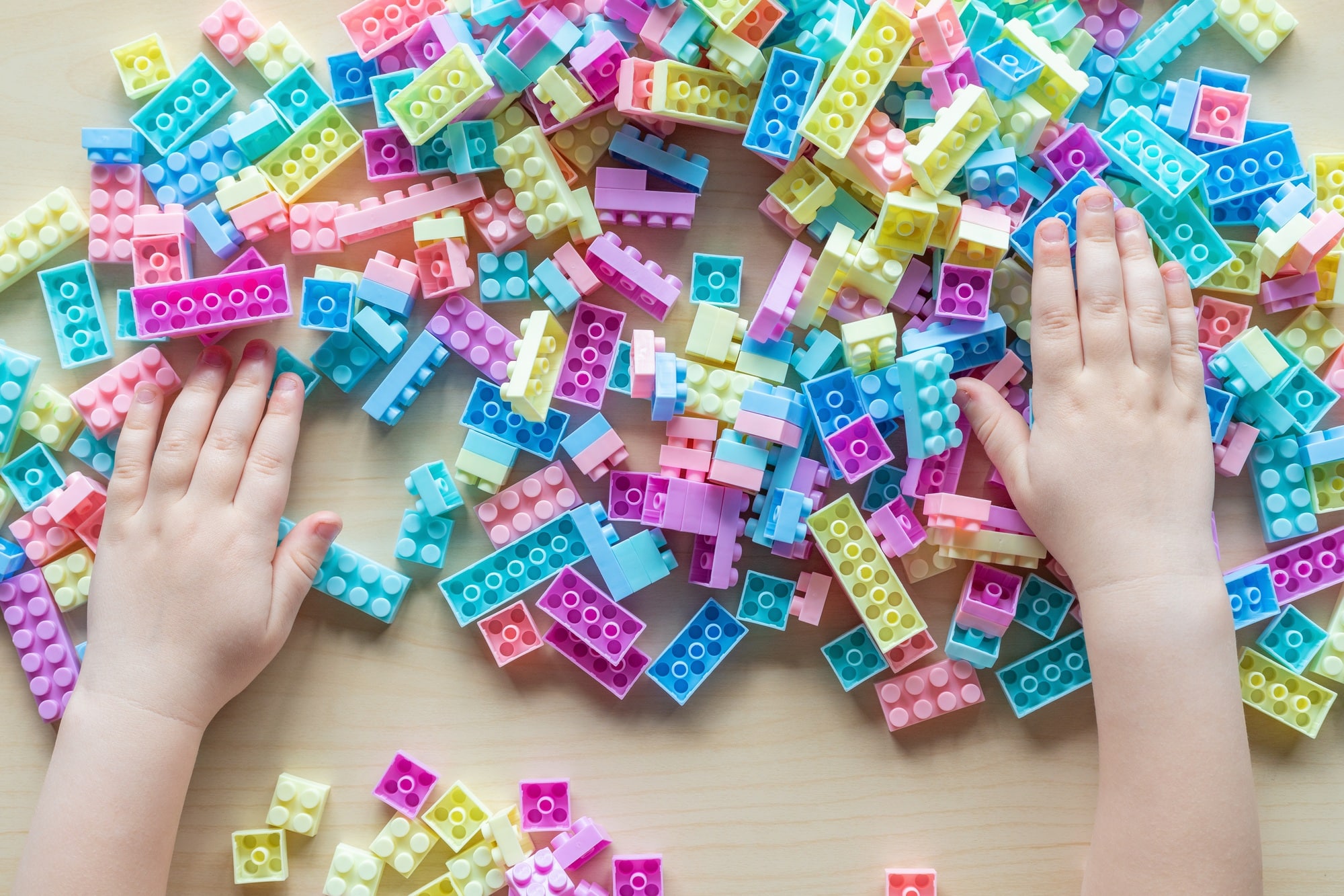 Little child playing colorful construction blocks at the table. Top view