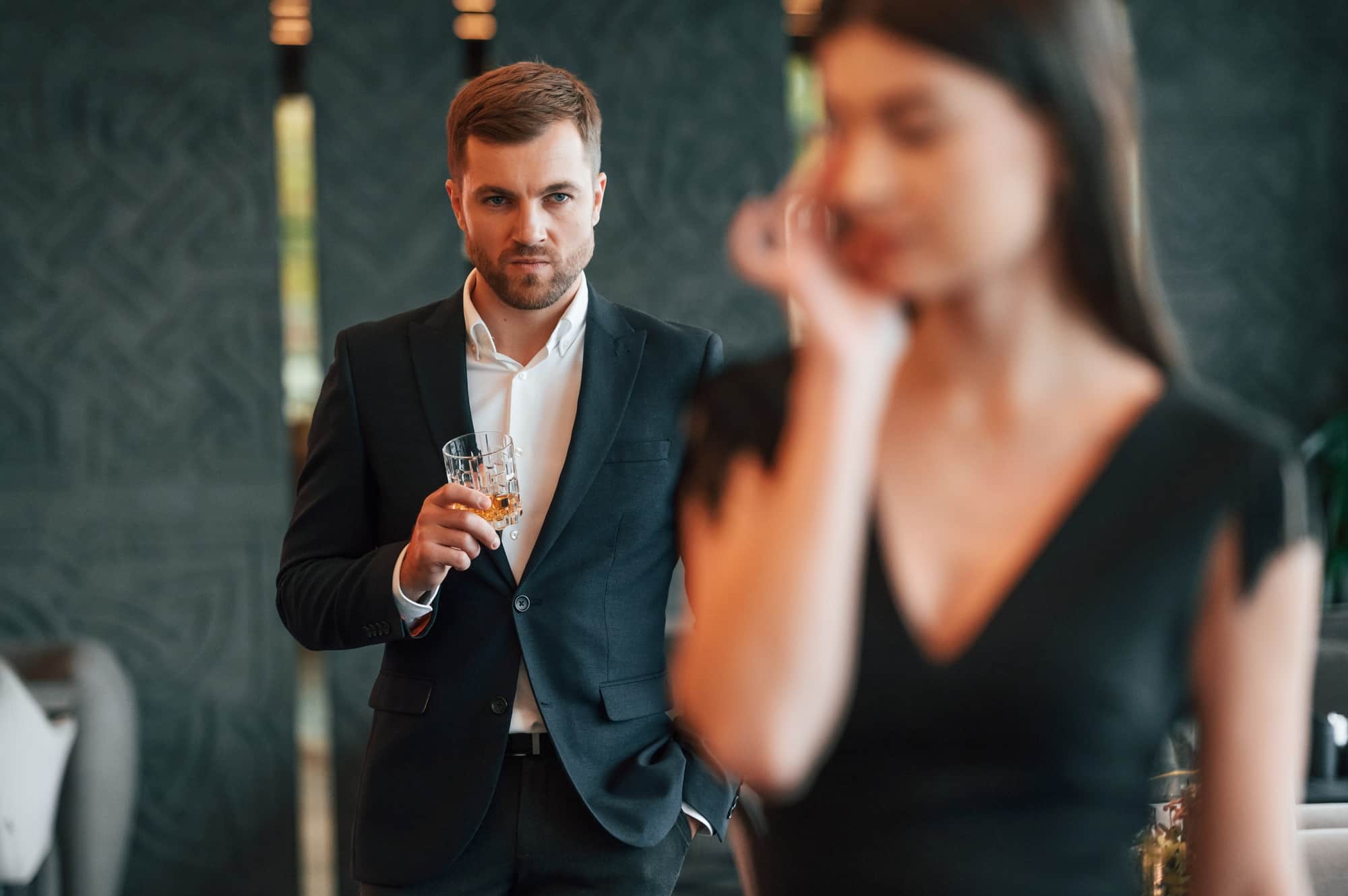 Man in black suit is angry at woman that is standing and crying