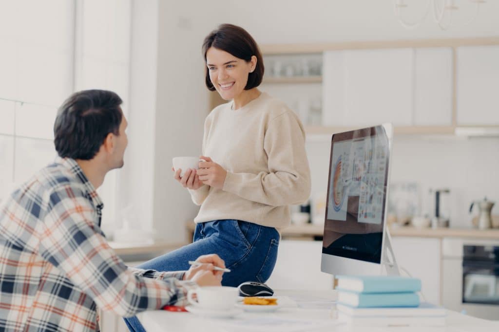 woman and man discuss renting apartment, pose in coworking space with computer