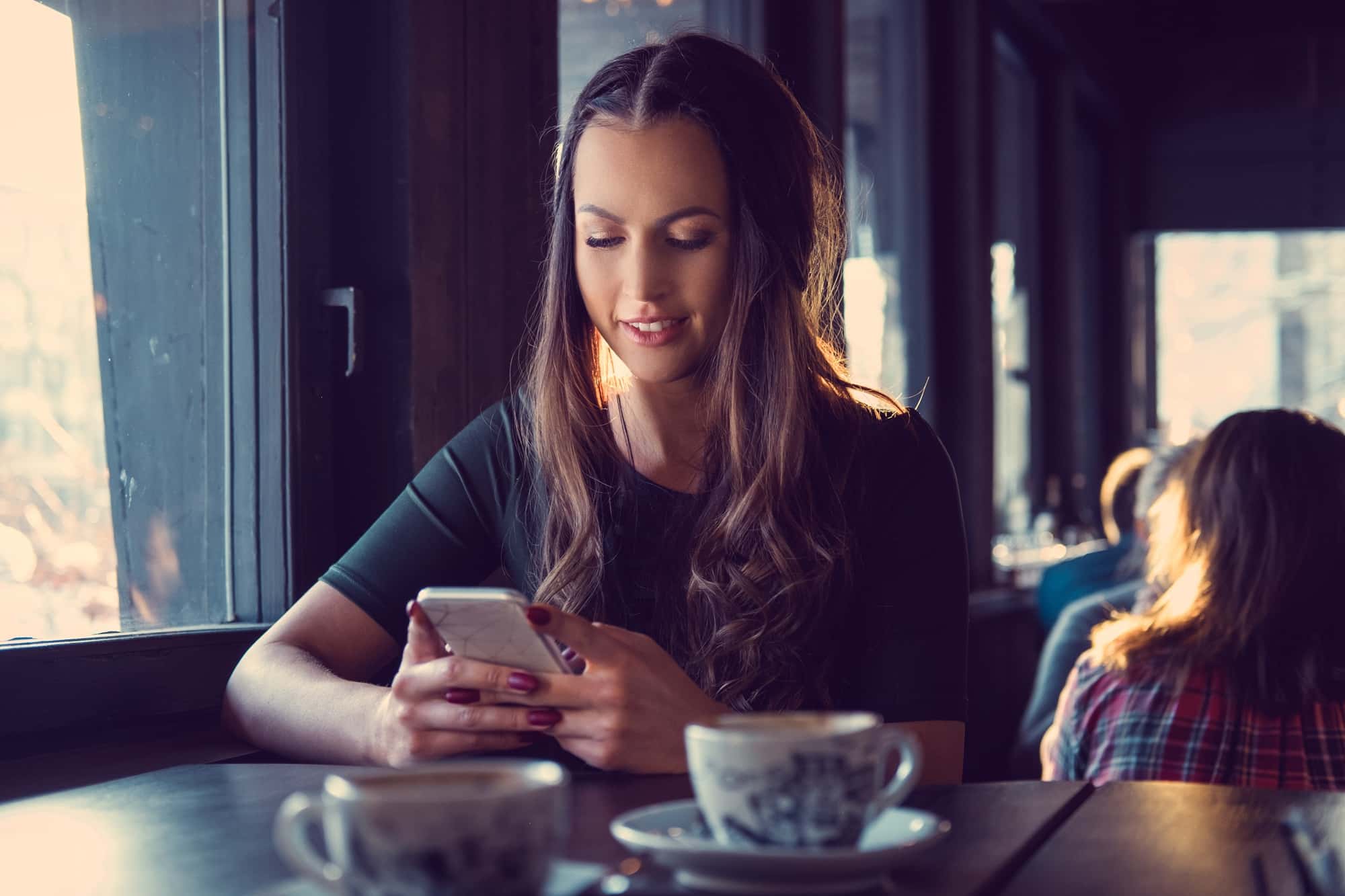 A woman texting an SMS in a cafe.