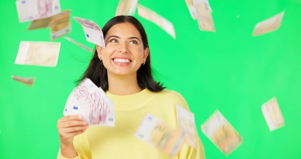 Happy woman, cash and money rain on green screen for winning, prize or lottery against a studio bac