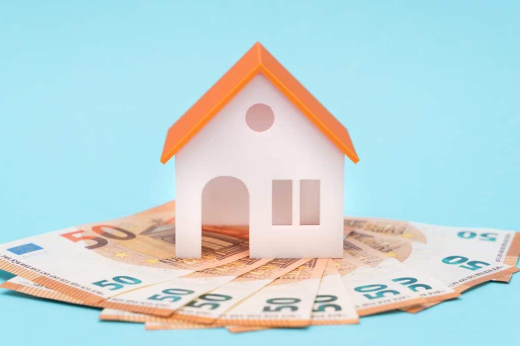 white toy house and euros on a blue background with free space for tex