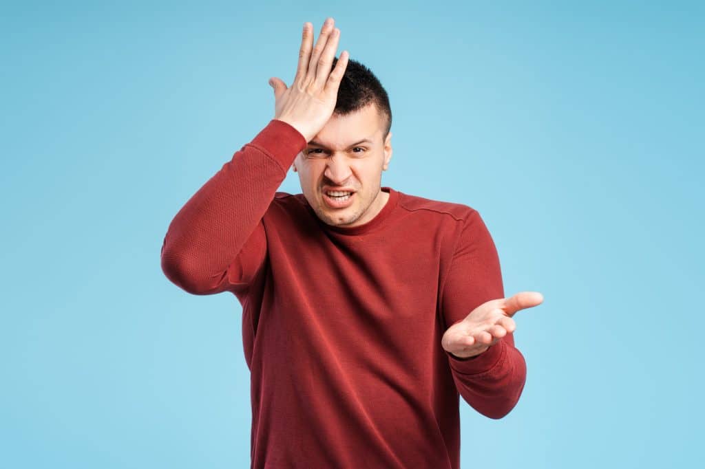 Young angry, annoyed man makes the gesture of questioning you in his mind, touching his head
