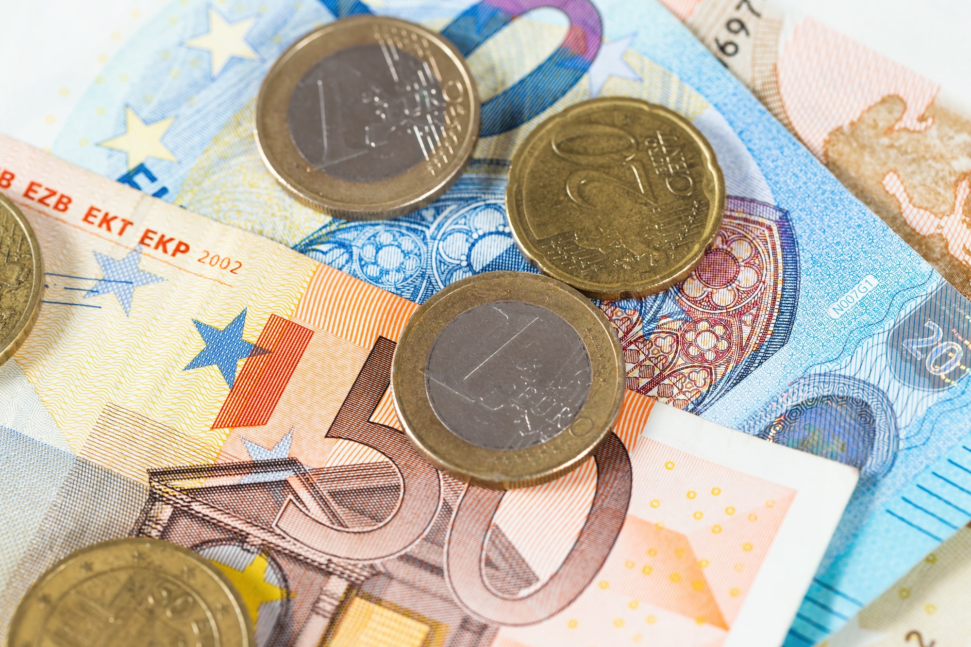 Euro coins lying on banknotes from above in close-up