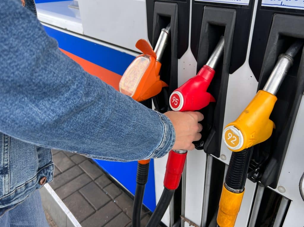 unrecognizable man taking of petrol pump filling fuel nozzle at gas station