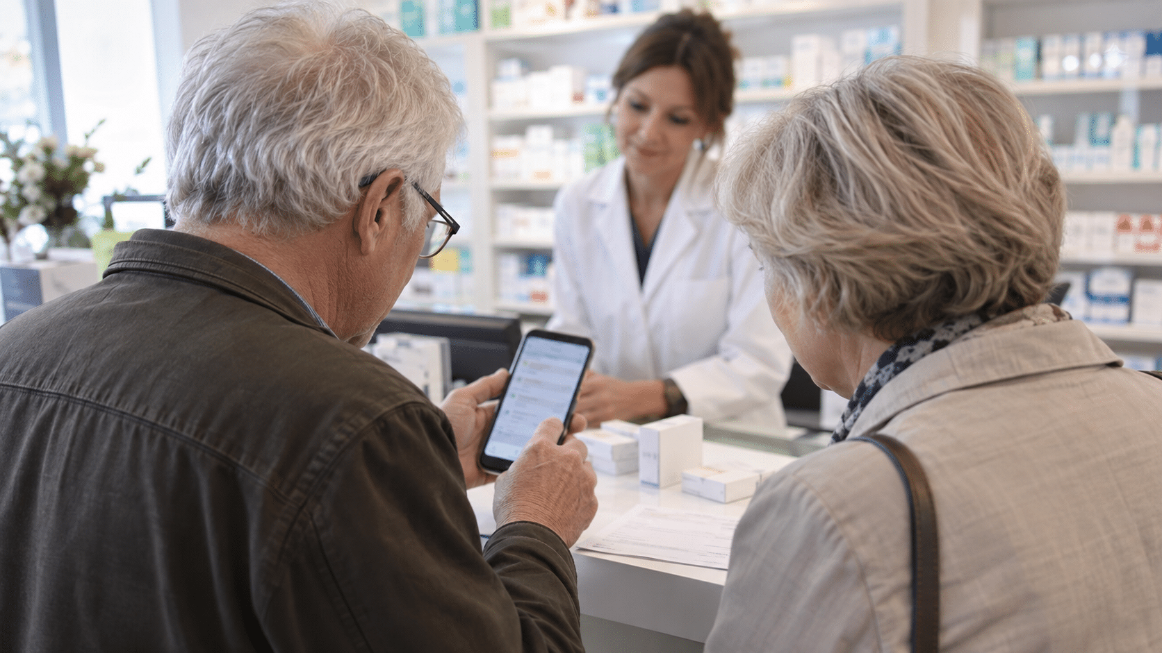 Un couple de seniors consulte un relevé de remboursement dans une pharmacie